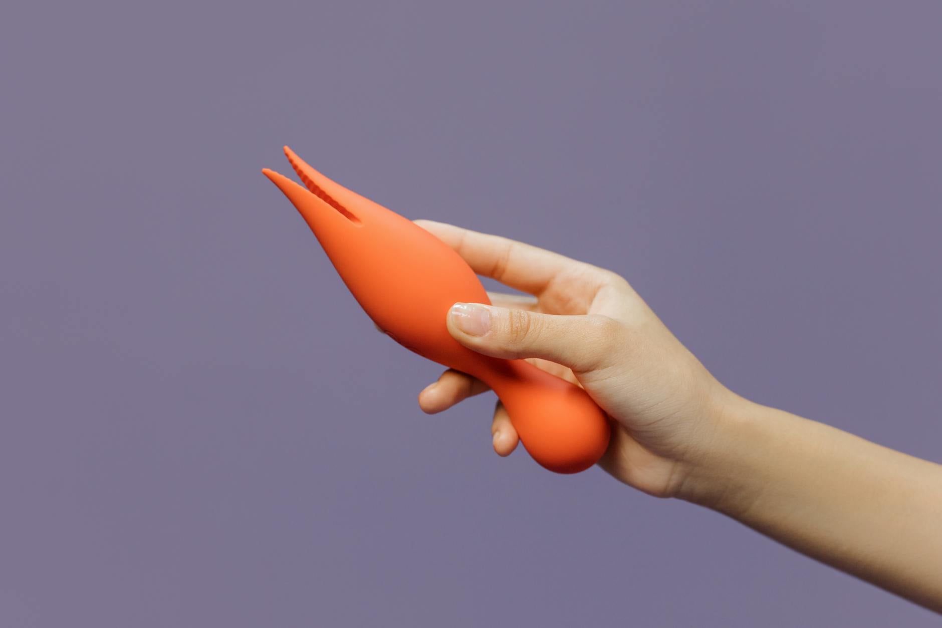 Hand holding a lemon-shaped vibrator against a minimalist purple background, representing tactile reconnection during emotional numbness.